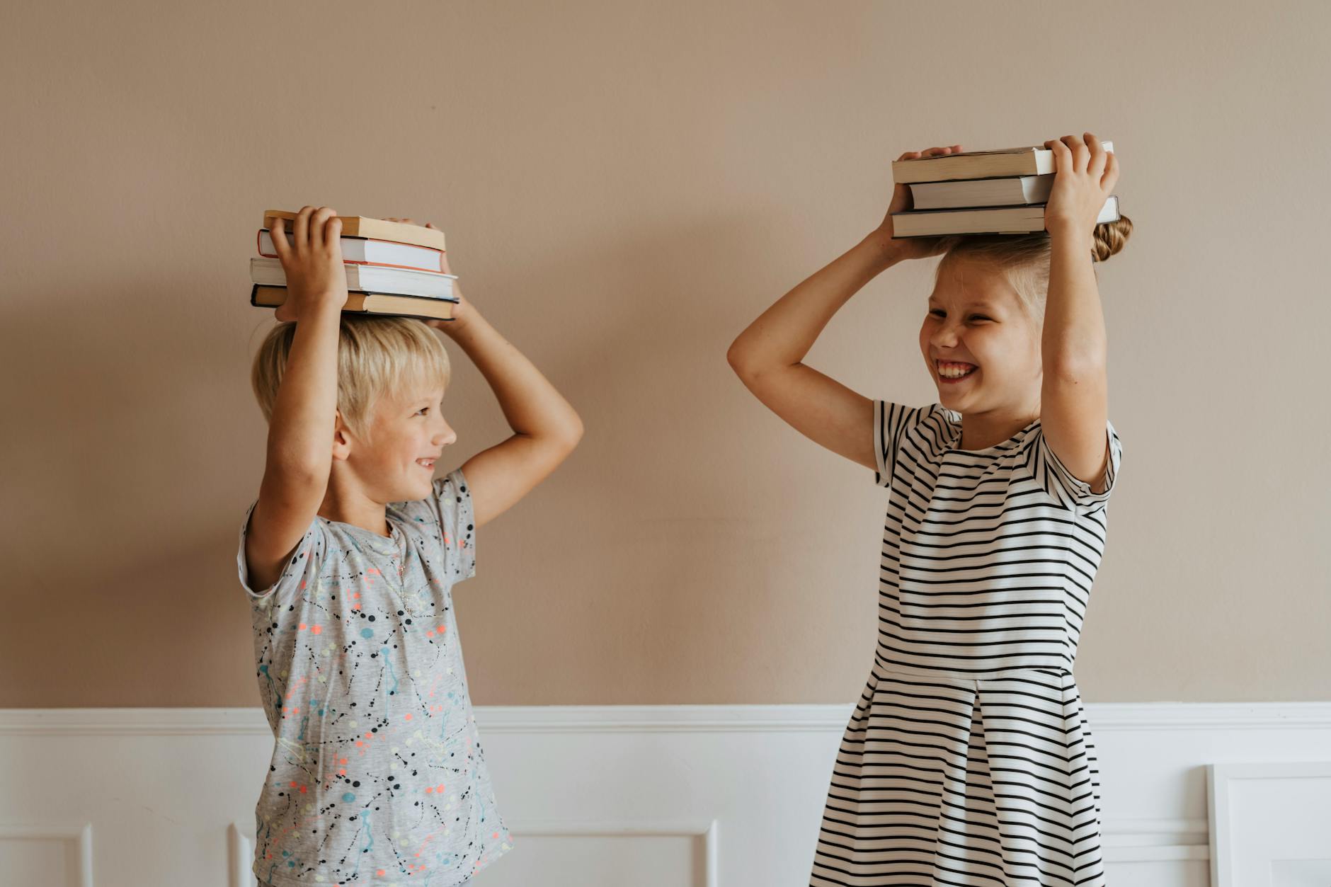 brother and sister with books on their heads