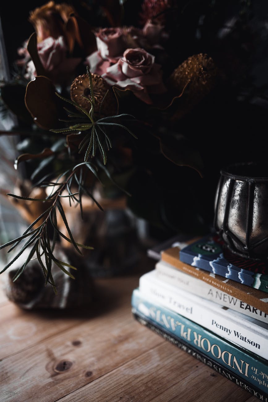 pile of books near a flower vase
