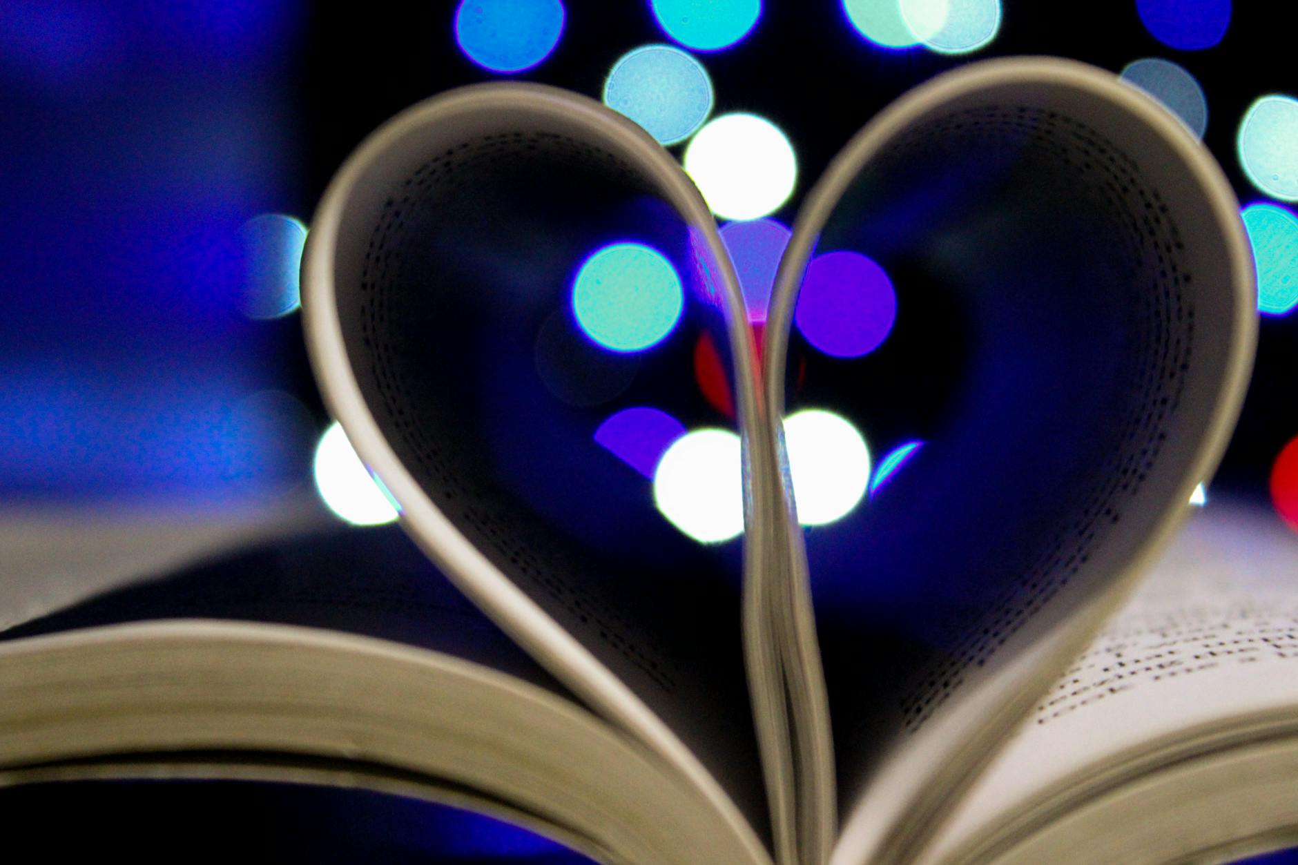 photo of bookpages folded into heart shape with bokeh light background